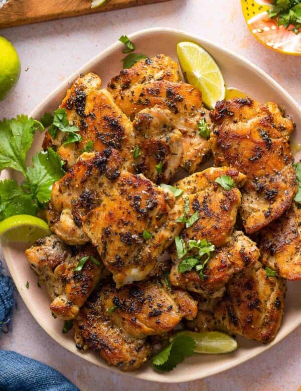 Cilantro Lime Marinated Chicken on a serving plate with lime wedges and fresh cilantro